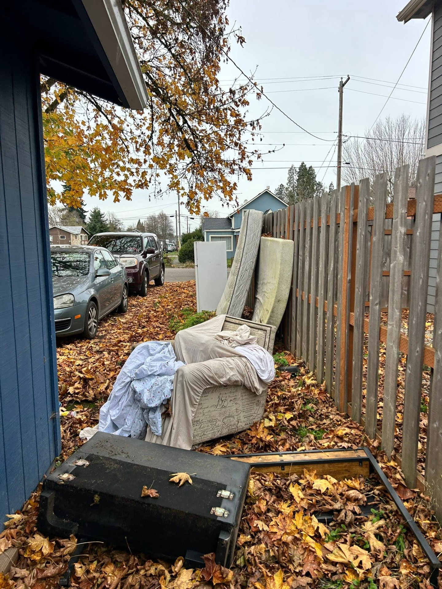 Before: mattresses, a chair and household debris piled along the fence in the side yard