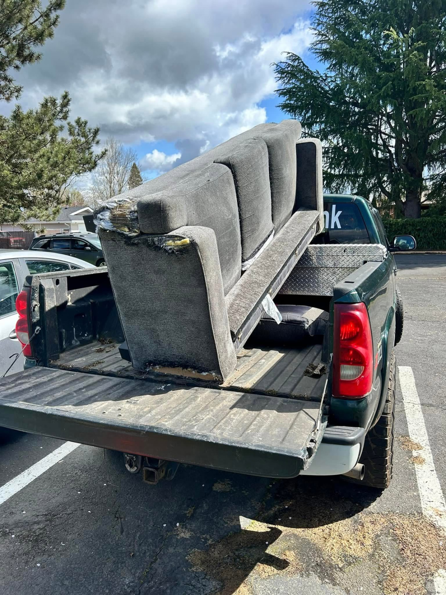 Worn couch loaded into a pickup truck bed for furniture removal